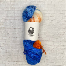 Load image into Gallery viewer, Ball of yarn with blue, orange, and white colors on a white brick wall background
