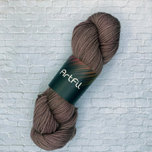 Load image into Gallery viewer, Brown skein of yarn with 'Artful' label on a light gray brick background