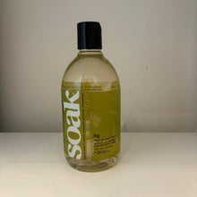 Load image into Gallery viewer, A bottle of Fig Soak cleaning solution with a black cap and olive-green label, standing on a white surface against a plain light gray wall.