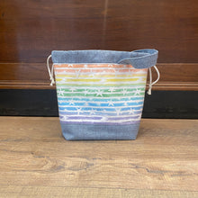Load image into Gallery viewer, A drawstring project bag with a multicolored geometric pattern and a gray denim-like material, featuring a wrist strap handle.