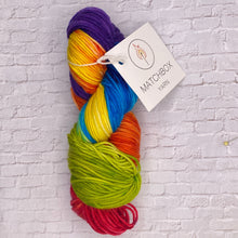 Load image into Gallery viewer, Multicolored yarn skein with a label on a textured white background