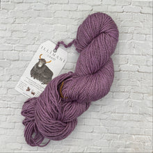 Load image into Gallery viewer, Purple skein of yarn with a label on a white brick background