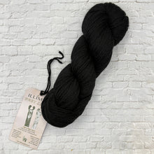 Load image into Gallery viewer, Black skein of yarn with a label on a white brick background