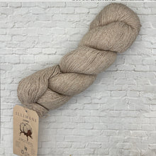 Load image into Gallery viewer, Ball of beige yarn with a label on a white brick wall background