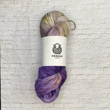 Load image into Gallery viewer, Yarn skein with a label on a white brick background
