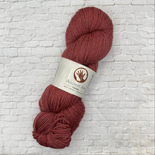 Load image into Gallery viewer, Ball of red yarn with a label on a white brick background

