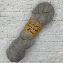 Load image into Gallery viewer, Gray skein of yarn with a label on a textured white background
