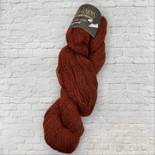 Load image into Gallery viewer, Brown skein of yarn with a label on a white brick background

