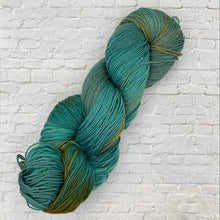 Load image into Gallery viewer, Green skein of yarn against a white brick wall background
