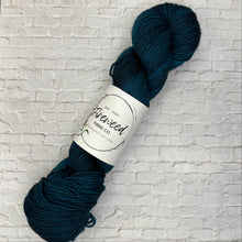Load image into Gallery viewer, Dark blue skein of yarn with a label on a light gray brick background
